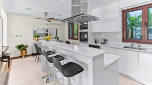 Cocina moderna con una isla central, taburetes de bar y un ventilador de techo.