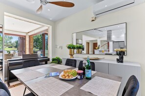 A dining area with a table set for four, a bottle of liquor, and a plate of food. - Villa 35 - Poseidon in Kouklia (Kouklia)
