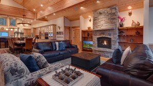 Una sala de estar acogedora con chimenea de piedra, sofás de cuero y un comedor con armarios de madera.