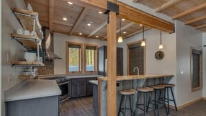 Una cucina moderna con isola centrale, sgabelli da bar e soffitto in legno.