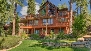 A multi-story wooden cabin with a balcony, surrounded by trees and a stone retaining wall. - Incline Oasis - Incline Village Lakeview - TLUXP (Incline Village)