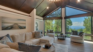 A modern living room with a large sectional sofa, two armchairs, and a coffee table. The room features large windows offering a view of the outdoors. - Incline Oasis - Incline Village Lakeview - TLUXP (Incline Village)