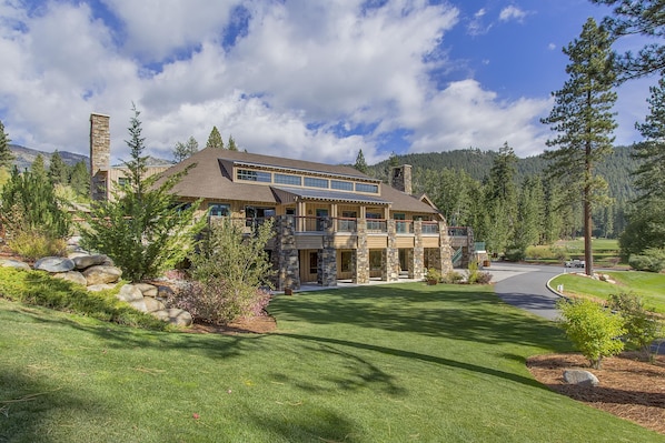 A large, two-story house with a stone facade, multiple windows, and a well-maintained lawn.