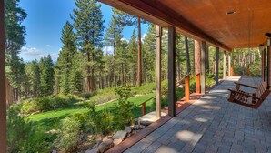 A covered outdoor area with a wooden deck, stone flooring, and a view of a forested landscape. - Incline Oasis - Incline Village Lakeview - TLUXP (Incline Village)