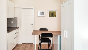 A compact kitchen with a wooden table, a black chair, and a white door.