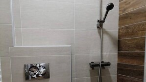 A small, modern bathroom with a toilet, a shower, and a wooden accent wall.