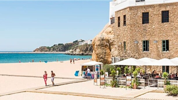 A stone building with a beach in the background.