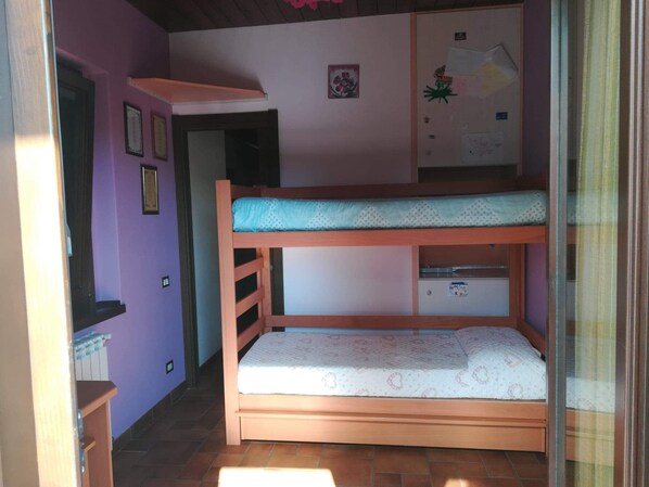 A bunk bed room with a small desk and a window.