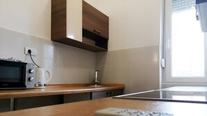Una cocina con microondas, cafetera y control remoto sobre la encimera.