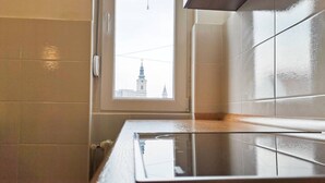 Una cocina con ventana, azulejos blancos y vistas a un edificio.