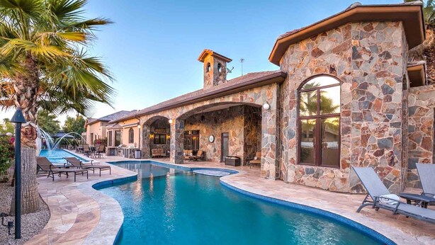 A pool area with stone walls, lounge chairs, and a clear blue pool.