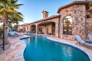 A pool area with stone walls, lounge chairs, and a clear blue pool. - Scottsdale Luxury Villa w/ Pool, Spa, Tennis, Pickleball, Volleyball and Theater (Scottsdale)