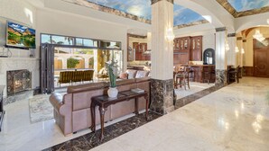 A spacious lobby with a high ceiling, a fireplace, a seating area, and a view of the outside.