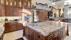 A spacious kitchen with wooden cabinets, granite countertops, and a central island with a sink.