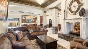 A spacious living room with a fireplace, leather sofas, and a chandelier.