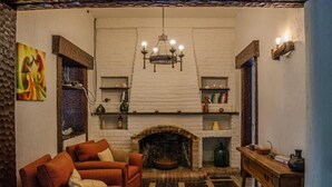A cozy living room with a fireplace, a sofa, and a wooden table. - Posada Los Cipreses (San Rafael)