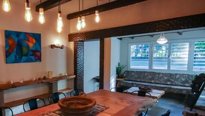 A dining area with exposed wooden beams, hanging light fixtures, and a colorful abstract painting. - Posada Los Cipreses (San Rafael)