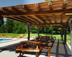 A wooden pergola with a pool and lounge chairs.