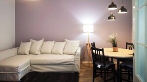 A cozy living room with a sofa, a dining table with chairs, and pendant lights.