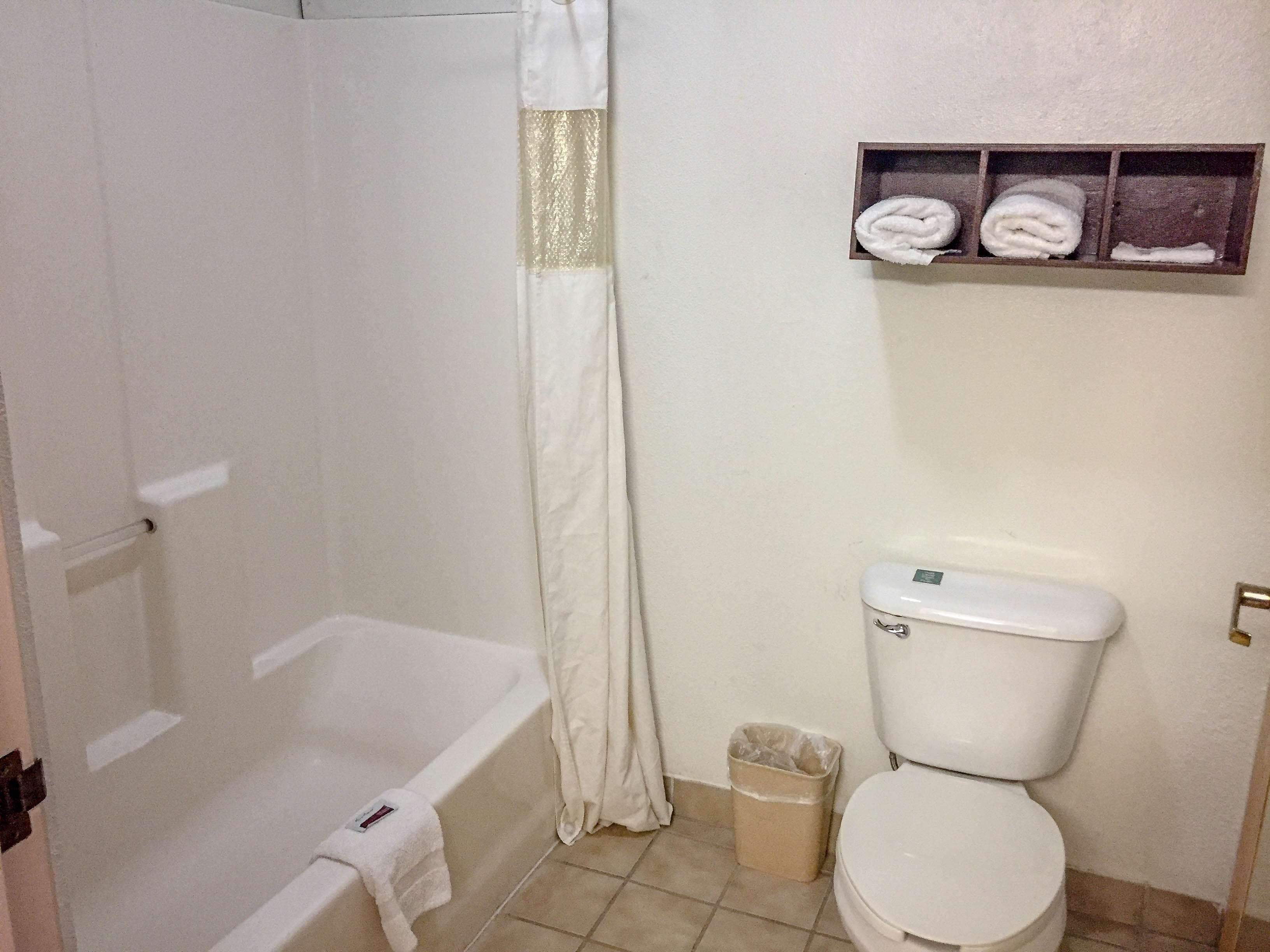 Een badkamer met een bad, toilet en een plank met handdoeken.