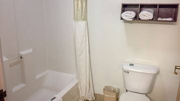 Een badkamer met een bad, toilet en een plank met handdoeken.