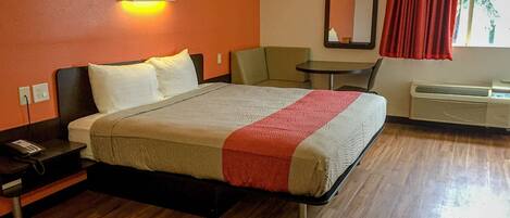 Una camera d'albergo con un letto, un comodino, una sedia e un tavolino.