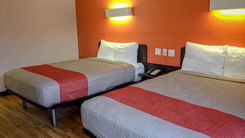 Two twin beds with grey and red bedding, a wooden floor, and a wall-mounted light fixture.