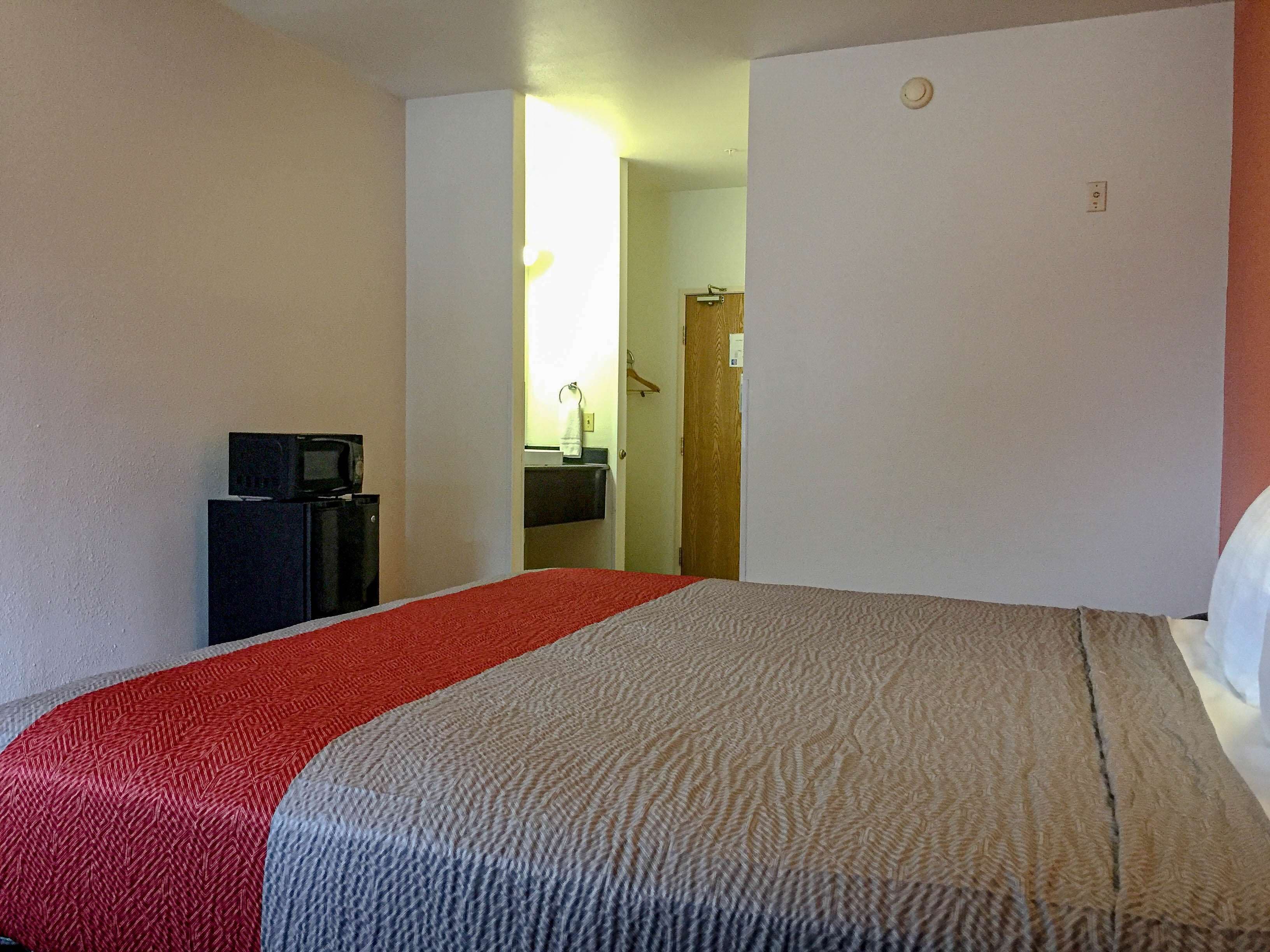 Una habitación de hotel con una cama, un televisor y un escritorio pequeño.