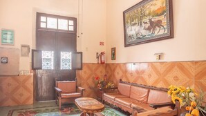 A cozy living room with a wooden sofa, a small wooden table, and a colorful tiled floor. - Hotel Margarita (Mérida)