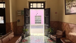 A lobby with a patterned floor, a ceiling fan, and a door leading outside. - Hotel Margarita (Mérida)