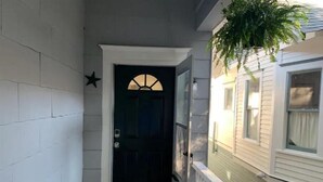 Uma entrada estreita com uma porta escura, uma estrela decorativa na parede e um degrau que leva a um alpendre.