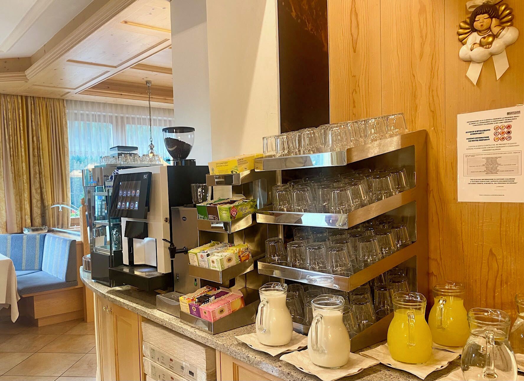 A hotel breakfast bar with a coffee machine, a variety of food items, and a selection of drinks.