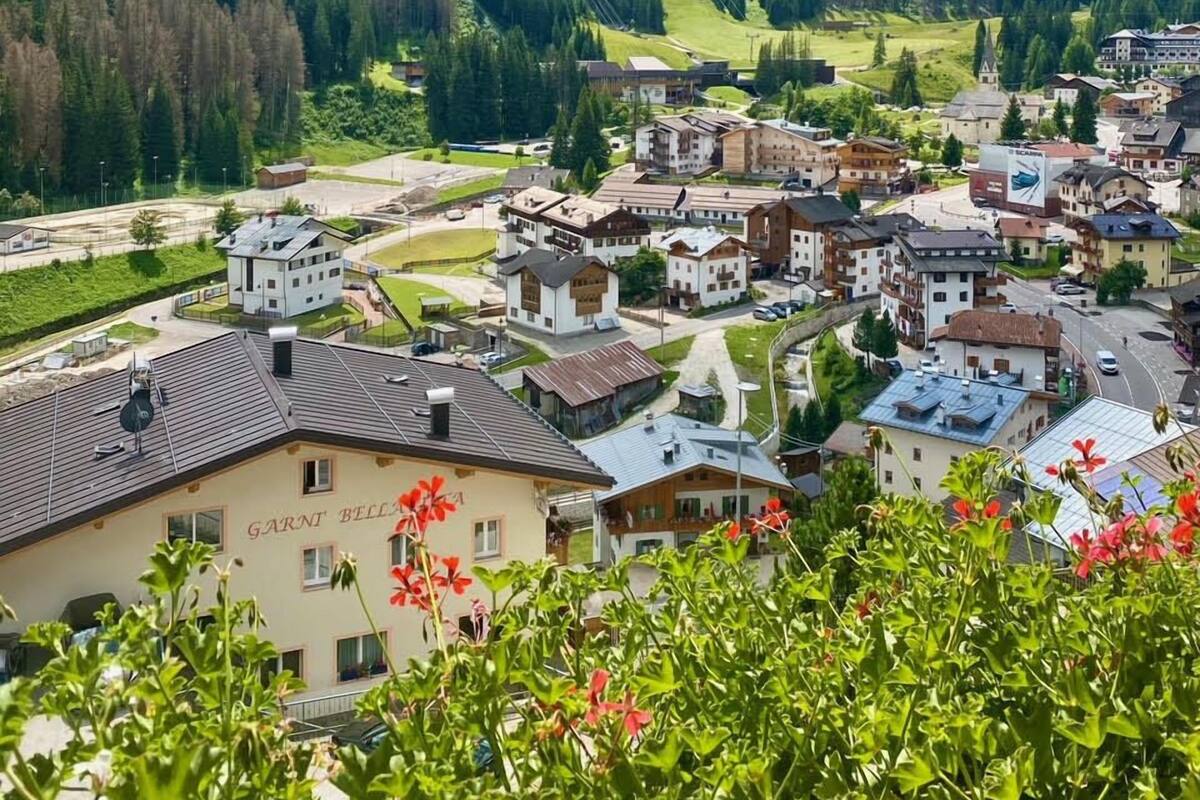 Eine beschauliche Stadt in den Bergen mit traditioneller Architektur, darunter ein Gebäude mit der Aufschrift 'GARNT BELL', umgeben von üppiger Vegetation und Bergen.