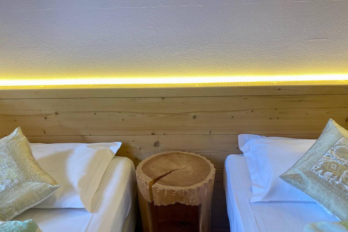 Ein Zimmer mit zwei Betten, jeweils mit Kissen und einem Nachttisch aus Holz.