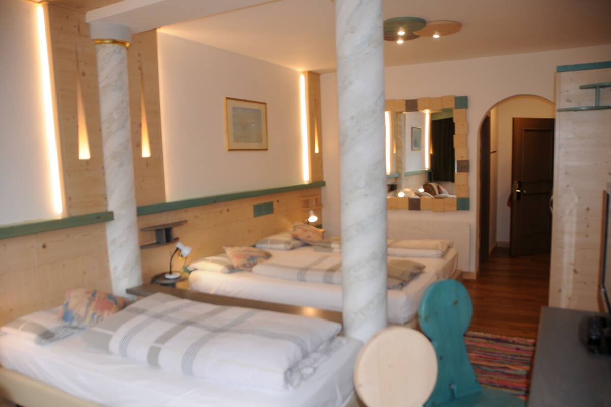 Ein Hotelzimmer mit drei Betten, einem Badezimmer und einem Spiegel.