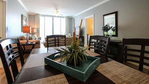 Uma área de refeições com mesa de madeira, cadeiras e uma planta decorativa central numa bandeja azul.