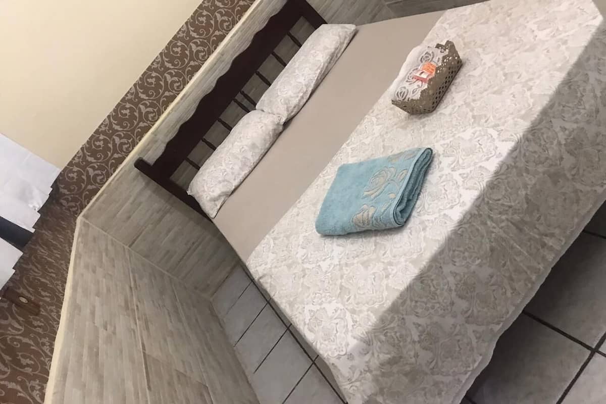 A hotel room with a bed, a window, and a decorative wall.
