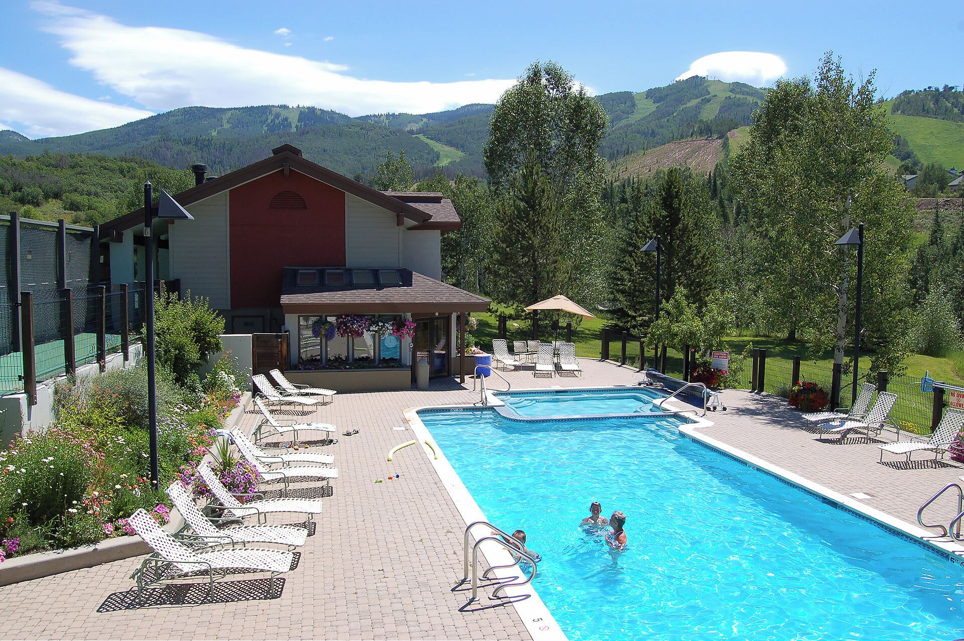 A swimming pool with lounge chairs and a building with a red facade.