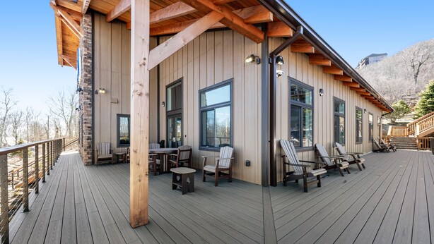 A wooden deck with outdoor seating and large windows. - Lovely ski-in/out condo with gorgeous mountain views and shared tennis court (Sugar Mountain)