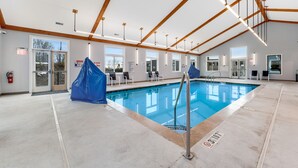 An indoor swimming pool with a clear view of the ceiling structure, a fire extinguisher, and a covered area. - Lovely ski-in/out condo with gorgeous mountain views and shared tennis court (Sugar Mountain)