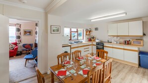A compact living space with a dining area, kitchenette, and a red sofa in the living room.