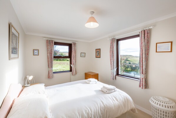 A bedroom with two beds, a wooden cabinet, a radiator, and a view of the outdoors. - Laghead Cottage -  a cottage that sleeps 6 guests  in 3 bedrooms (Gatehouse of Fleet)