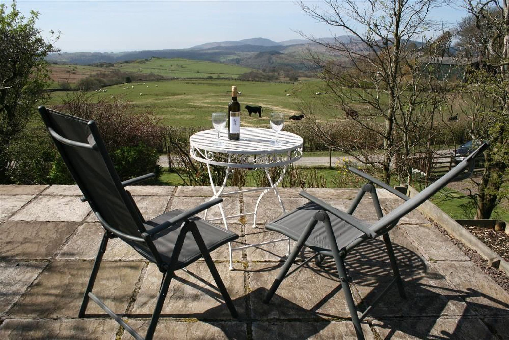 A patio with a table and chairs overlooking a rural landscape.