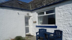 A white building with a blue trim, a door, and two blue chairs outside. - Barnacle -  a cottage that sleeps 4 guests  in 2 bedrooms (Southwick-Sandyhills)