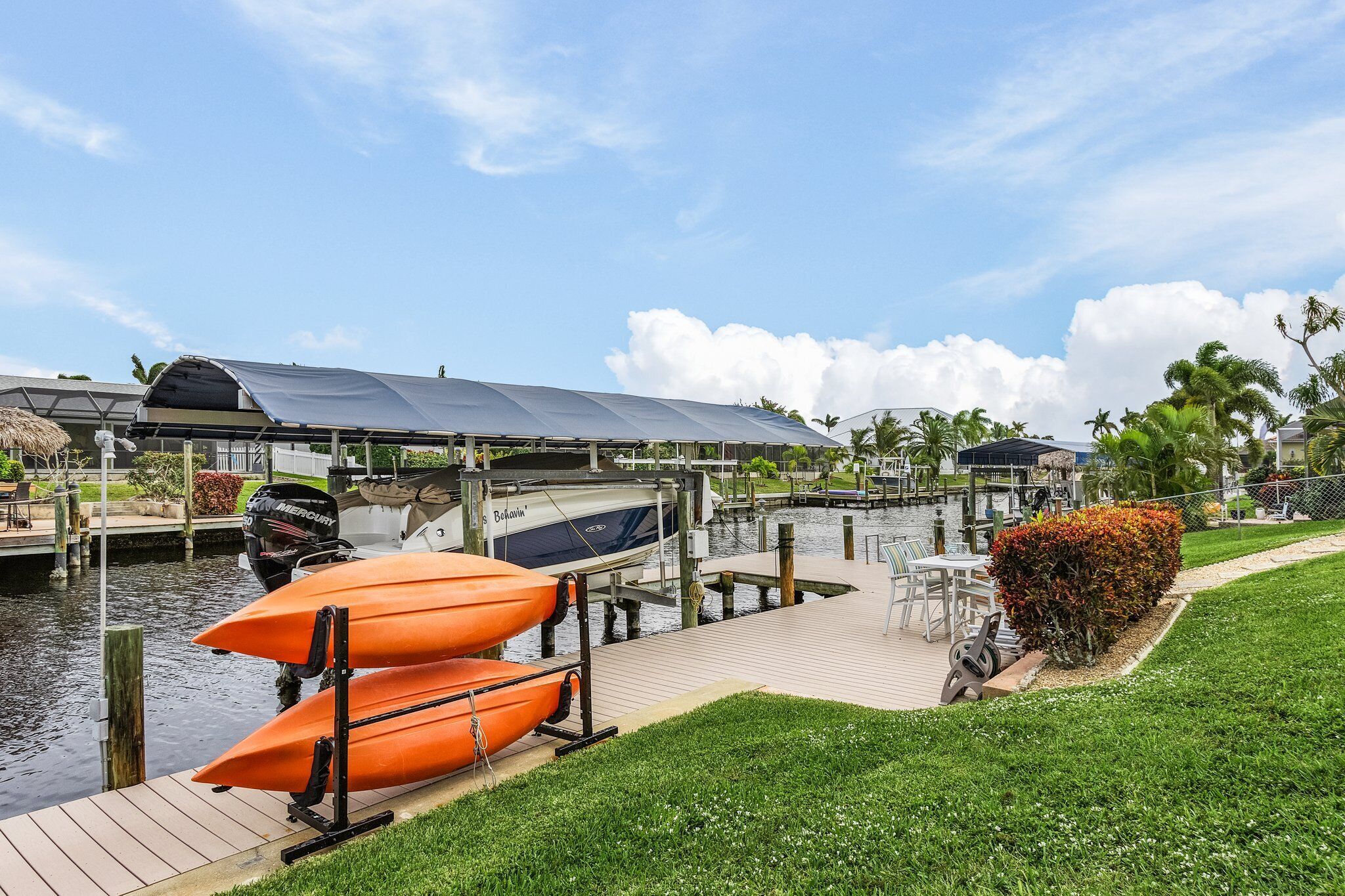 A marina with boats docked, a covered area, and a grassy area with a bench.
