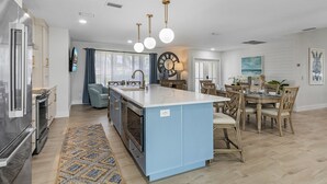 Une cuisine moderne dotée d’un îlot central, d’appareils électroménagers intégrés et d’un coin repas agrémenté d’un lustre.