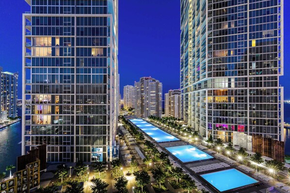 A modern high-rise hotel with multiple floors, a rooftop pool, and a waterfront view.