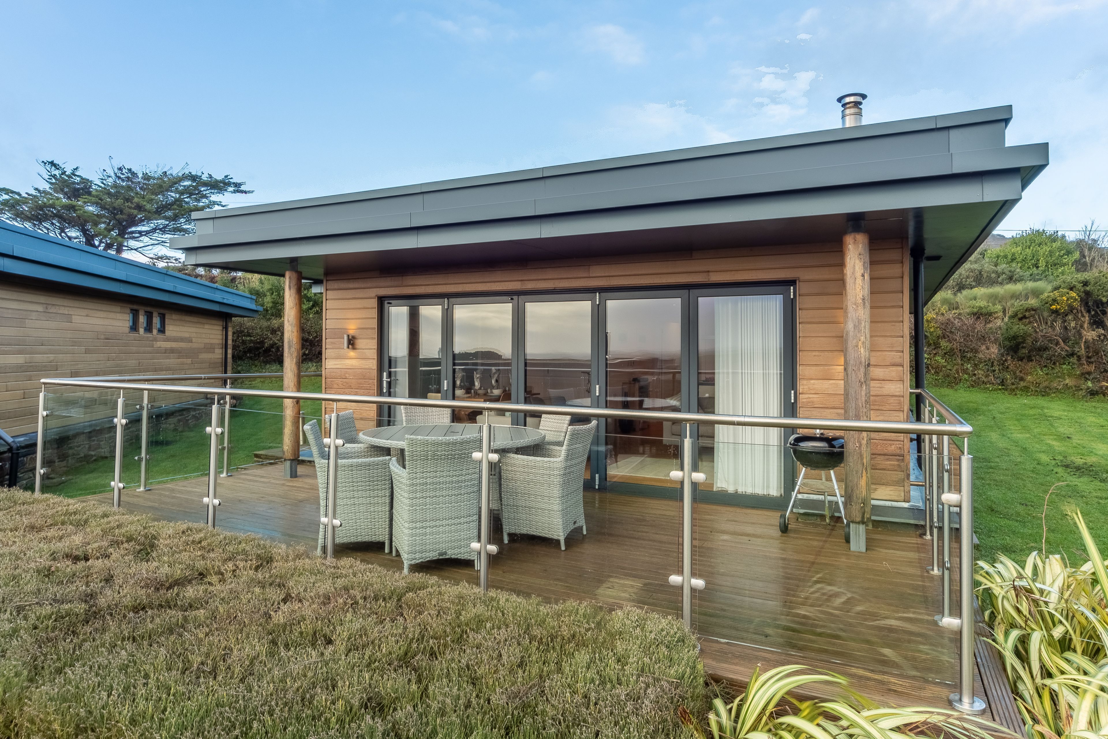 A modern house with a deck, outdoor furniture, and a barbecue grill.