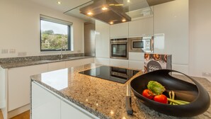 Una cocina moderna con encimera de granito, electrodomésticos de acero inoxidable y un tazón negro con verduras.