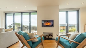 Una sala de estar moderna con sofás color turquesa, sillas de madera y una chimenea.